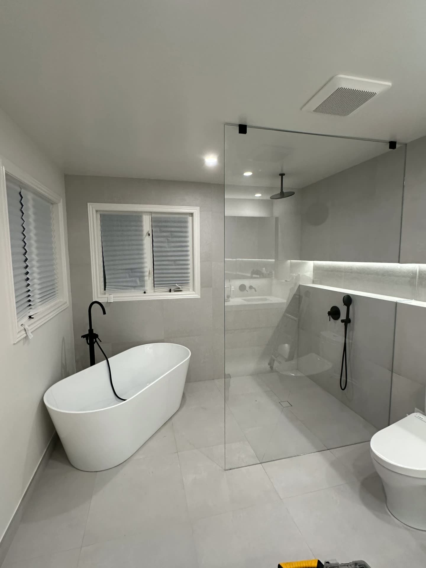 Frameless fixed glass shower panel beside a freestanding tub